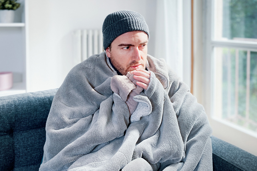Man feeling cold at home with home heating trouble