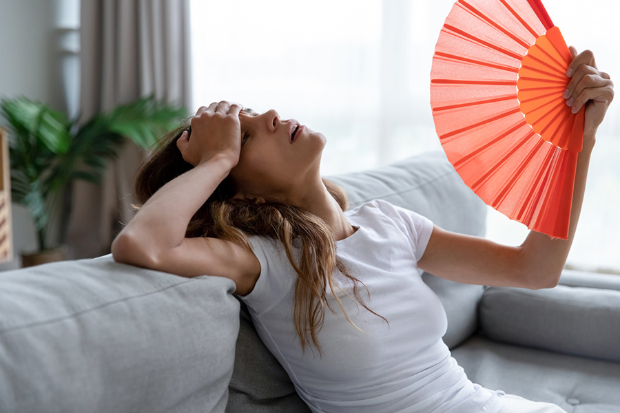 Exhausted girl using paper waver, suffering from hot summer weather